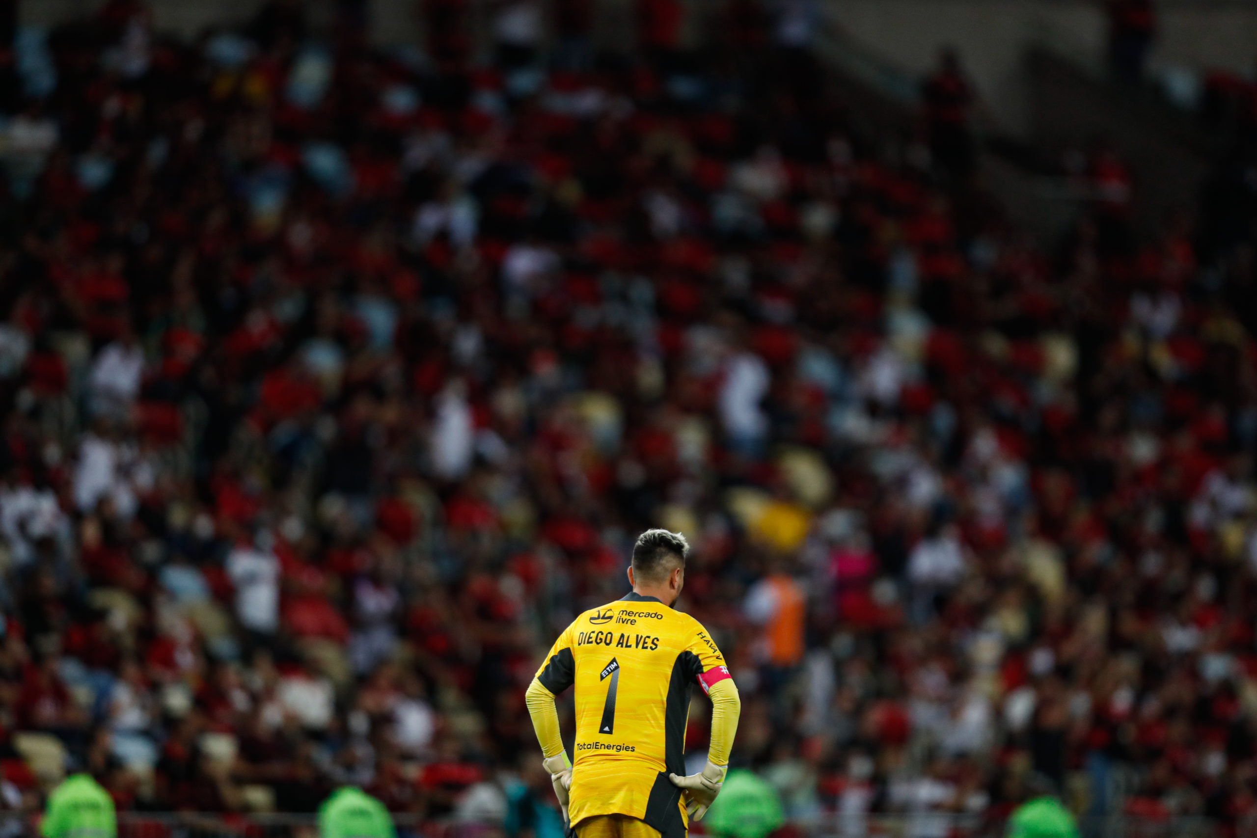 Diego Alves e a torcida do Flamengo desfocada ao fundo no estádio