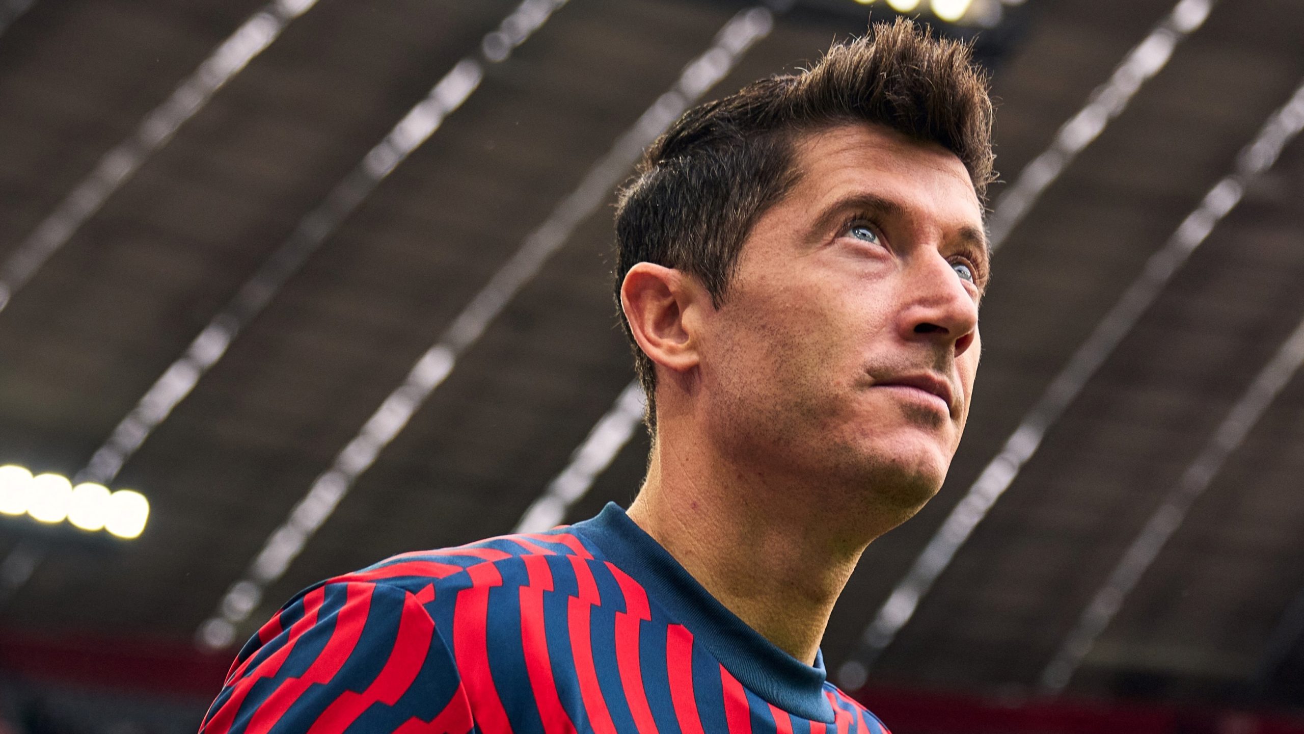 Robert Lewandowski olhando para cima enquanto entra em campo com uniforme de treino do Bayern de Munique.
