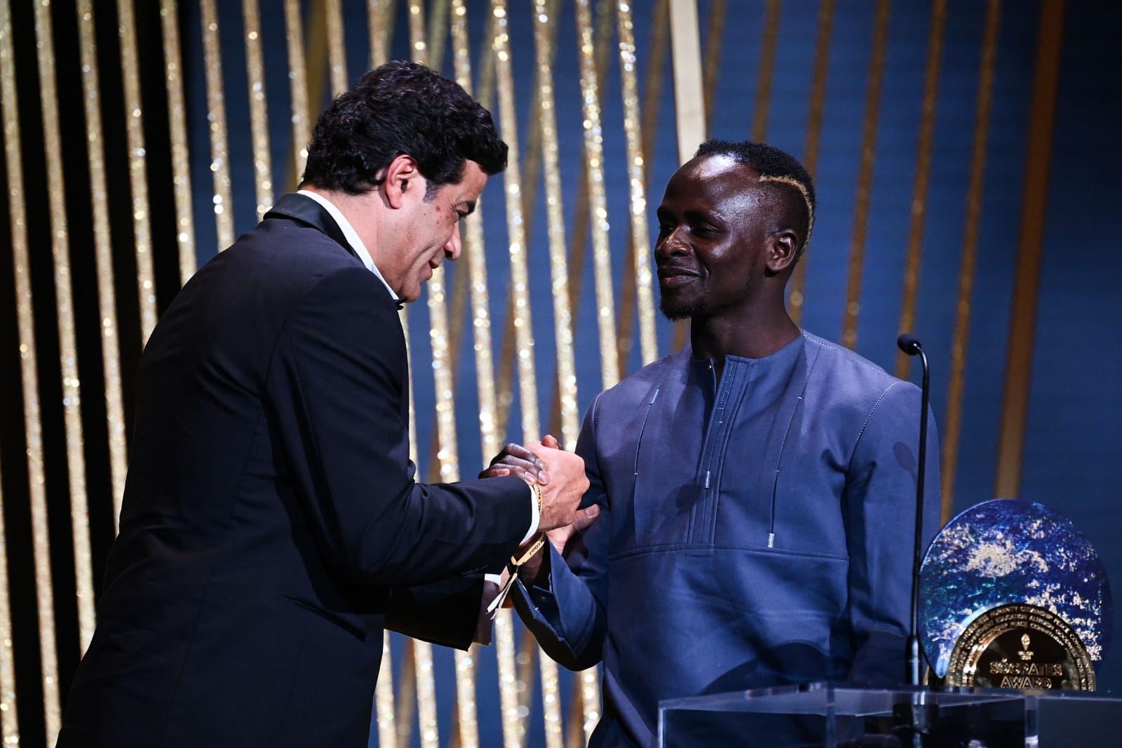 Raí, de terno preto e à esquerda, cumprimenta o senegalês Sadio Mané, à direita com vestimenta cinza, na entrega do Prêmio Sócrates