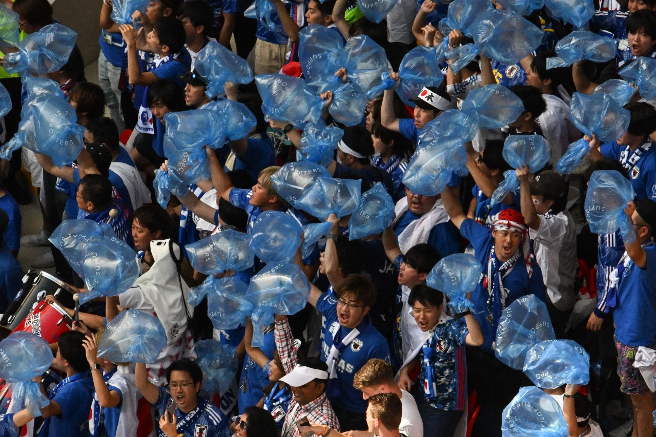 Torcedores do Japão fazem a festa com sacos de lixo levados para limpar as arquibancadas