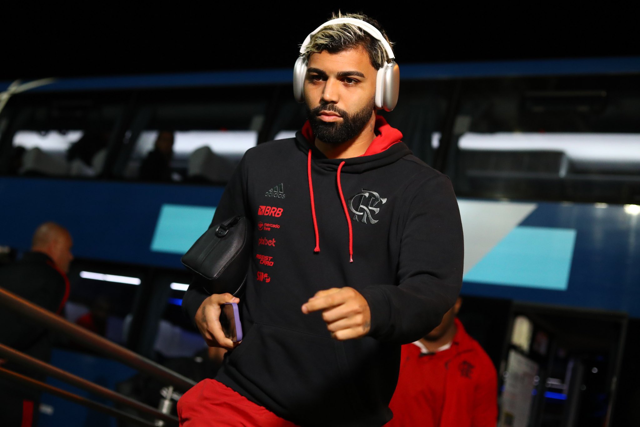 Gabigol concentrado ouvindo música no fonte com a bolsa dele na mão e caminhando em direção ao vestiário