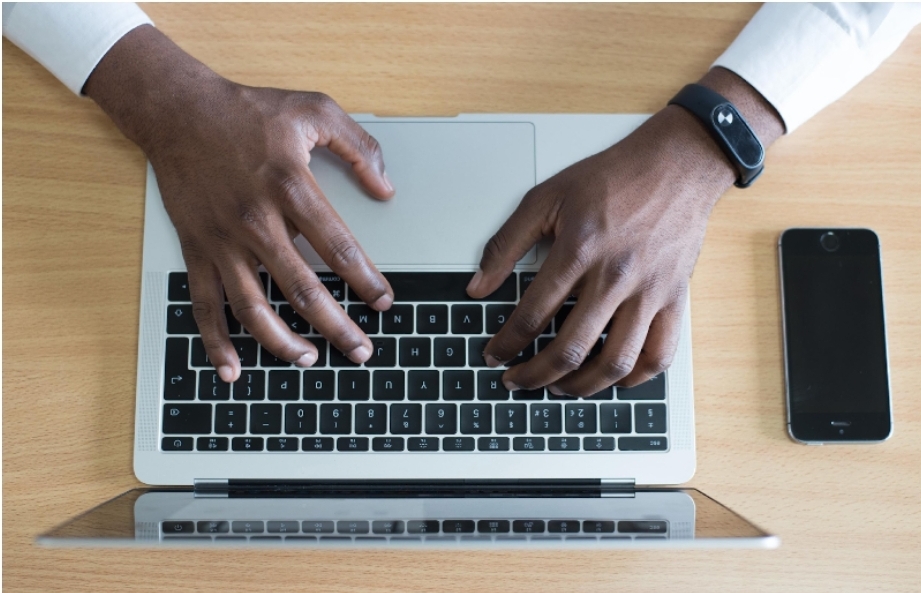 Mãos de homem negro teclando em notebook, vistas de cima