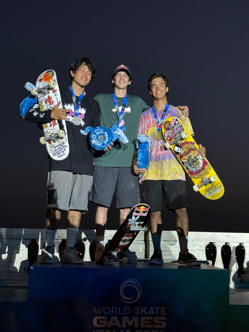 Guilherme Khury e Augusto Akio abraçados com o terceiro colocado na final do vertical do skate